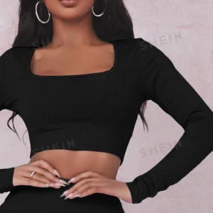 Svart ribbad croppad topp från SHEIN - Snygg svart ribbad topp från SHEIN med långärmad design och en fyrkantig urringning. Perfekt för både vardag och fest! Den croppade stilen ger en trendig look. Passar bra till jeans eller kjol för en chic outfit.