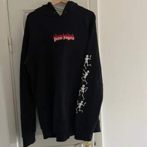 Säljer en svart hoodie från Palm Angels med coola skelettmotiv längs ärmen och ett rött logotryck på bröstet. Den är gjord av 100% bomull och är i storlek L, modellen är oversized så passar även större storlekar. Hör av er vid frågor eller kom med ett prisförslag!