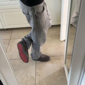 Grå sneakers från Christian Louboutin - Snygga grå sneakers i mocka från Christian Louboutin med den ikoniska röda sulan. Skorna har snörning och en stilren design som passar perfekt för en trendig look. Tar även emot byten mot andra skor eller annat!!😇😇Sulan är lite sliten!