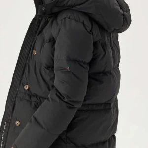 Svart dunjacka med huva - Säljer en snygg svart dunjacka med huva, perfekt för kalla vinterdagar. Jackan har långa ärmar och knappar framtill. Den är både varm och stilren. Köptes flera år sedan men användes enbart i några månader sen dess har den bara legat i garderoben 