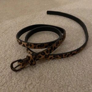 leopardmönstrat skärp - Ett vintage skärp i leopardmönster, skitcool textur (typ päls). 105 cm långt, kortaste hålet på 73 och längsta på 88 cm