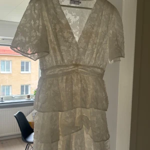 Vit spetsklänning från Retro & Icone - Elegant vit klänning i spets från Retro & Icone. Den har en v-ringad design med korta ärmar och ett fint volangdetaljerat liv. Perfekt för somriga tillfällen. Själv hade jag denna på min student vilket blev perfekt