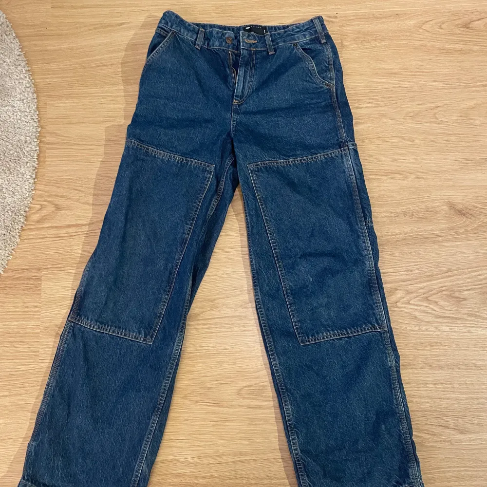 Säljer ett par blå jeansbyxor från ASOS Design. Byxorna har en loose passform med raka ben och förstärkta knäpartier. Stora i passformen . Jeans & Byxor.