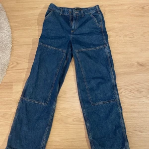 Blå jeansbyxor från ASOS Design - Säljer ett par blå jeansbyxor från ASOS Design. Byxorna har en loose passform med raka ben och förstärkta knäpartier. Stora i passformen 
