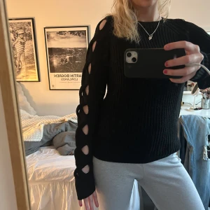 Svart stickad tröja med hålmönster - svart stickad tröja med cut out längs ärmarna, så cool! 