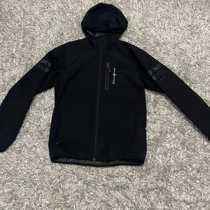 Sail Racing jacka - Säljer en svart Sail Racing jacka i superbra skick. Jackan har inte använts mycket då den är i för stor storlek. Passar bra till regnväder