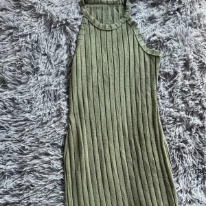 Grön ribbad klänning - Snygg grön ribbad klänning i ett mjukt material. Den är ärmlös och har en hög halsringning. Oanvänd. 