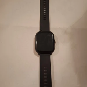 Svart smartklocka med laddare - Säljer en stilren svart smartklocka i mycket bra skick. Den har en fyrkantig skärm och ett justerbart armband. Perfekt för både vardag och träning. Laddare med USB-anslutning ingår. Passar till alla tillfällen och är enkel att använda.