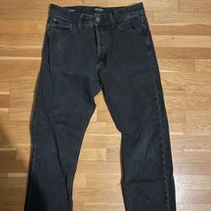 Svarta Jack&Jones jeans Relaxed/Chris - Säljer ett par svarta jeans i modellen Relaxed/Chris. De har en avslappnad passform och är perfekta för vardagsbruk. Jeansen har en klassisk design med fem fickor och knappgylf. De är i bra skick och redo för en ny ägare!