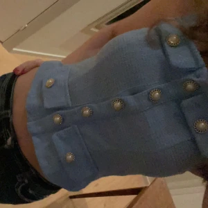 Blå topp med pärlknappar - Blå topp med dekorativa pärlknappar framtill. 