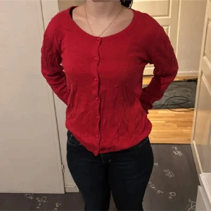 Jultröja❤️ - Säljer en snygg röd kofta med pärldetaljer. Koftan har långa ärmar och knäpps med knappar framtill. Perfekt för att lägga till en färgklick i garderoben! perfekt till jul och nyår❤️❤️