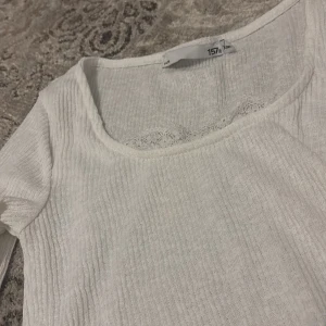 Vit ribbad topp - Säljer en stilren vit ribbad topp med lång ärm och rund halsringning. Perfekt för lager-på-lager eller som den är. Enkel och mångsidig i garderoben.