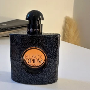 Black Opium Eau de Parfum från Yves Saint Laurent - Black opiun🖤 YSL: Yves Saint Laurent. Denna parfym kombinerar noter av vanilj, vita blommor och kaffe för en djärv och modern upplevelse. Flaskan är elegant svart med glittrande detaljer och en rund etikett i mitten. Bara testad så 99% kvar (nypris 1000kr)