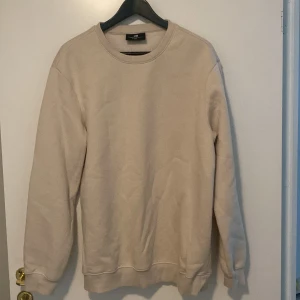 Beige sweatshirt från H&M - Säljer en stilren beige sweatshirt från H&M i storlek M. Den har en avslappnad passform och är perfekt för både vardag och mysiga stunder. Tröjan är långärmad och har en klassisk rund halsringning. Perfekt för höst och vår!
