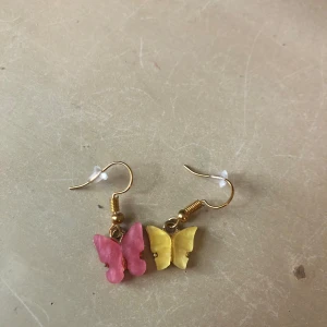 Örhängen - Fina fjärilsörhängen i gul/rosa. Rengörs innan köp och pluppar medföljer.