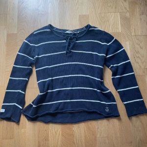 Marinblå randig tröja  - Marinblå tröja från Iconic Sport med vita ränder och ett ankare broderat längst ner. 