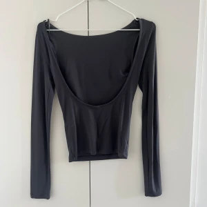 Långärmad med öppen rygg - Nästan helt oanvänd tajt långärmad med öppen rygg, i en jättefin mörkgrå färg.  Använd Max 1 gång.  