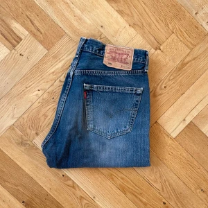 Levi’s 501 Jeans - Vintage Levi's 501 jeans i en unik blå/grå tvätt. Har diskret lagning på vänster ben. Fint vintage skick. Storlek 33/34. Mått: Innerbenslängd: 86 cm, Benöppning: 21 cm, Midja: 41 cm. Köpet är slutgiltigt.