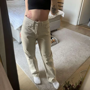 Beige jeans från Yoke - Säljer ett par snygga beige jeans från Monki i storlek S. De är högmidjade och har en straight passform. Perfekta för både vardag och fest! De är i bra skick och väldigt bekväma att ha på sig. Passa på att fynda dessa stilrena byxor!