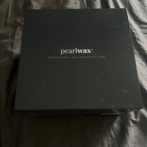 Pearlwax Professional Hair Waxing Kit - Säljer ett Pearlwax Professional Hair Waxing Kit för hemmabruk. Innehåller en vaxvärmare, flera påsar med hårdvaxpärlor och träspatlar för applicering. Perfekt för att enkelt och smidigt ta bort oönskat hår hemma. Instruktioner för användning medföljer. Allt är i nyskick och redo att användas!