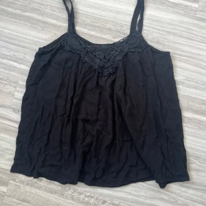 Svart linne med spetsdetaljer - Säljer ett svart linne med fina spetsdetaljer vid halsen. Den är från Indiska och I storlek M. Linnet har smala axelband och är tillverkat i ett mjukt och bekvämt material. 💝