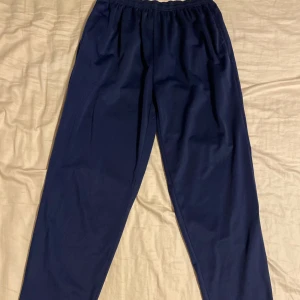 Mörkblå träningsbyxor i polyester - Sköna långbenta träningsbyxor. Sitter som M/L. Tveka inte att höra av dig om du har frågor eller vill ha fler bilder!