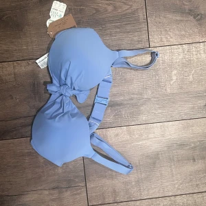 Blå bikiniöverdel från Calzedonia - Snygg blå bikiniöverdel från Calzedonia med knytning framtill. Tillverkad av återvunnen polyester, vilket gör den både stilren och miljövänlig. Perfekt för sommarens alla badäventyr. Justerbara axelband för bästa passform.