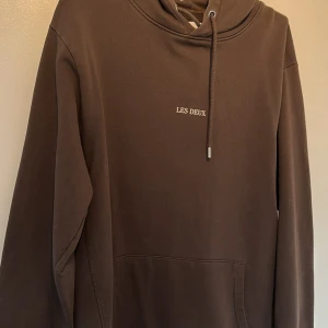 Brun hoodie från Les Deux  - Säljer en stilren brun hoodie från Les Deux. Tröjan har en klassisk design med justerbar huva och en praktisk magficka. Perfekt för en avslappnad look.