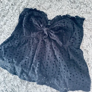 Svart prickig topp från Shein - Säljer en svart topp från Shein med prickigt mönster och knytning framtill. Toppen har en söt volangdetalj vid axlarna och är perfekt för en somrig look💕(priset kan diskuteras)