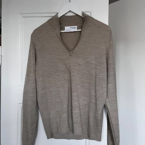 Beige tröja med dragkedja  - Säljer en stilren beige tröja. Tröjan har en dragkedja vid halsen och är tillverkad i ett mjukt material. Perfekt för en avslappnad och snygg look. Hör av dig vid minsta fråga eller fundering!