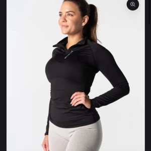 Svart långärmad  - Snygg och funktionell svart långärmad träningströja med dragkedja vid halsen. Perfekt för träning och aktiviteter utomhus. Tröjan har en tight passform som ger bra rörelsefrihet.