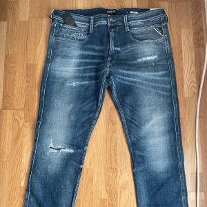 Jeans från Replay - Snygga blå jeans från Replay, helt oanvända med prislappen kvar. En klassisk femficksdesign och slitna detaljer. De har en knappgylf och är perfekta för en avslappnad stil. 