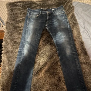 Blå jeans från Replay - Säljer ett par snygga blå jeans från Replay, modell Rocco. De har en klassisk femficksdesign och en lätt slitning för en cool look. Perfekta för en avslappnad stil.