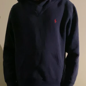 Mörkblå hoodie från Ralph Lauren - Säljer en riktigt snygg hoodie från Ralph lauren.              Modellen är 170 och den sitter bra på han. Skicket på hoodien är väldigt bra med inga synliga defekter. storleken är 14/16 år vilket motsvarar typ Xs