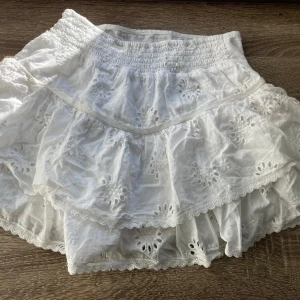 Vit kjol från Brownie - En vit kjol från Brownie med broderade blommönster och volanger. 