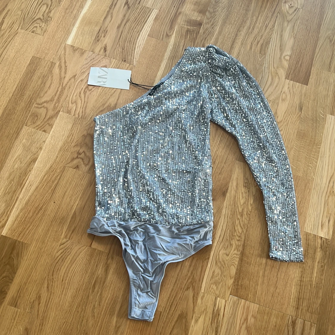 Glittrig oneshoulder body i silver