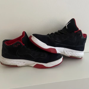 Svarta och röda sneakers från Nike - Snygga svarta sneakers med röda och vita detaljer från Nike. Skorna har en klassisk design med snörning och en vit sula med röda inslag. Perfekta för en sportig look.