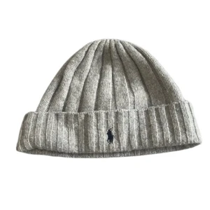 Grå mössa från Polo Ralph Lauren - Snygg grå mössa från Polo Ralph Lauren med broderad logotyp framtill. Perfekt för kyliga dagar med stilren design och mjukt material.