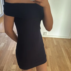 Mörkblå offshoulder klänning från Kappahl - Snygg mörkblå offshoulder klänning från Kappahl. Perfekt för en stilren look med sin tighta passform och korta längd. Klänningen är tillverkad i ett mjukt material som ger en bekväm känsla. Ett måste i garderoben för den som gillar enkel elegans.