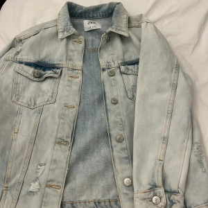 Ljusblå jeansjacka från Zara - Säljer en ljusblå jeansjacka från Zara med slitna detaljer och knappar framtill. Passar mig som brukar ha xs/s i jackor❤️