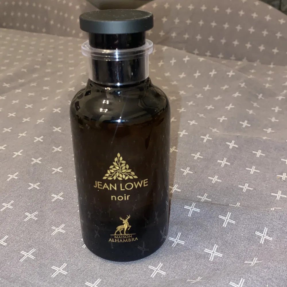 . Jean Lowe Noir från Maison Alhambra har en stilren design med gyllene detaljer. Perfekt för den som söker en sofistikerad doftupplevelse. Luktar som ombre nomad från Louis Vuitton. Endast använd 2 gånger. . Perfume.