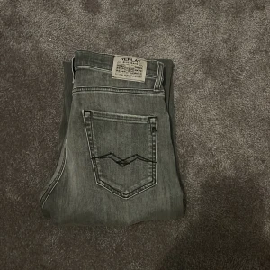 Grå jeans från Replay - Snygga grå jeans från Replay med en klassisk femficksdesign. De har en straight passform och är tillverkade i ett slitstarkt denimtyg. Perfekta för en stilren look.