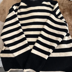 Randig tröja från Zara - Säljer en stilren svart och vit randig tröja från Zara. Tröjan har långa ärmar och ribbade muddar vid ärmslut och nederkant. Den är använd endast en gång och är strl M