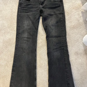 Svarta bootcut jeans från Gina Tricot - Snygga svarta bootcut jeans från Gina Tricot med dubbla knappar i midjan och knappar på bakfickorna. 