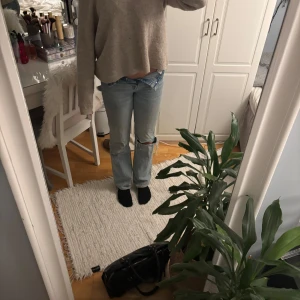 Ljusblå jeans med slitningar - Säljer ett par ljusblå jeans med slitningar på knäna. De har en hög midja och en straight passform. Perfekta för en avslappnad stil.