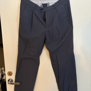 Grå kostymbyxor - Snygga grå kostymbyxor med en klassisk passform. De har en knapp och dragkedja framtill samt fickor på sidorna. Perfekta för en stilren look. Storlek Us 38r