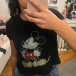 Svart Mickey Mouse t-shirt - Säljer en svart t-shirt med ett stort tryck av Mickey Mouse på framsidan och texten 'The One and Only Mickey Mouse Tour' på baksidan. Strl 170 men passar xs. Perfekt för Disney-fans! 🖤