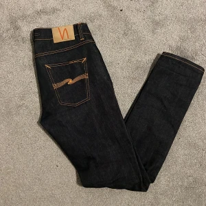 Mörkblå jeans från Nudie slim W29 - Snygga mörkblå jeans från Nudie med klassisk femficksdesign och orange kontrastsömmar. Nypriset ligger på 2500kr men jag säljer de för 800kr, priset går självklart att diskutera, modellen heter lean Dean dry Japan selvage 
