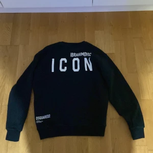 Svart tröja från Dsquared2 med tryck  - Snygg svart tröja från Dsquared2 med texten 'ICON' och 'IBRAHIMOVIC' på baksidan. Framsidan har ett tryck av en muskulös person och text. Perfekt för den som vill sticka ut med stil.  Och man kan diskutera om priset 