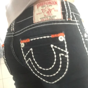 Mörkblå jeans från True Religion - Snygga mörkblå jeans från True Religion med vita kontrastsömmar. Byxorna har en låg midja och en bootcut passform som framhäver figuren. Perfekta för en trendig look. de står storlek 29 på de. Jae 155 o de e lite för långa. storlek s-xs är jag vanligtvis. 